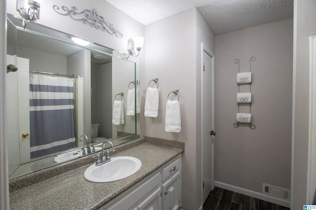 bathroom featuring wood finished floors, toilet, a textured ceiling, and visible vents
