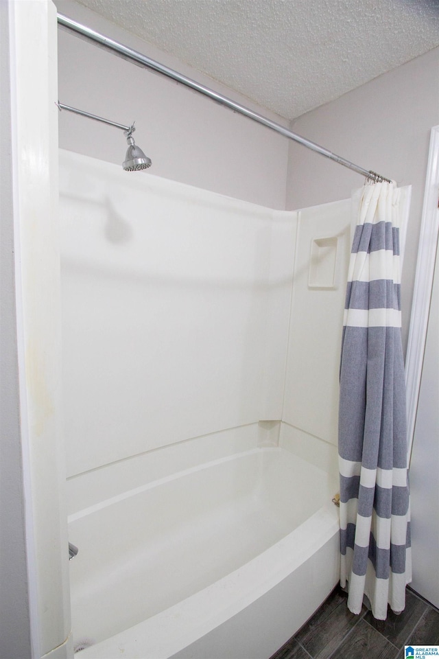 full bathroom featuring wood tiled floor and a textured ceiling