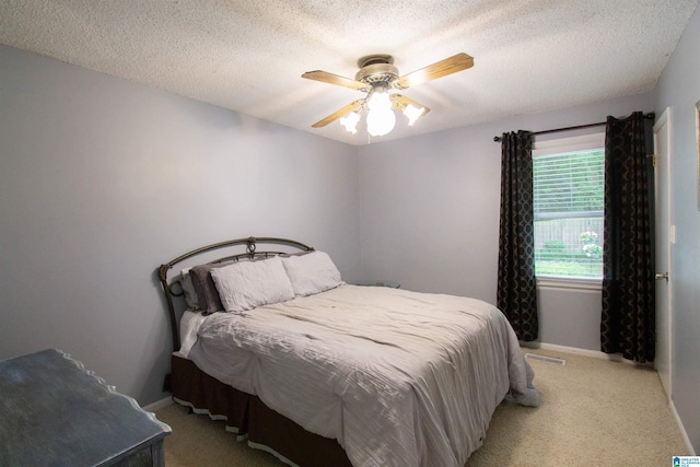 bedroom with baseboards, a textured ceiling, ceiling fan, and light carpet