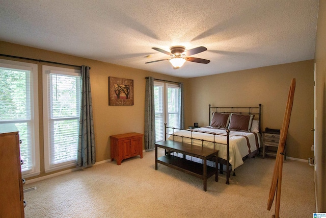 bedroom featuring baseboards, ceiling fan, light carpet, and a textured ceiling