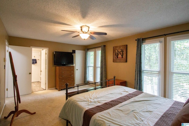 carpeted bedroom featuring a textured ceiling, ceiling fan, and ensuite bath