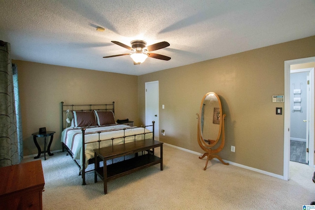 bedroom with a ceiling fan, baseboards, light colored carpet, and a textured ceiling