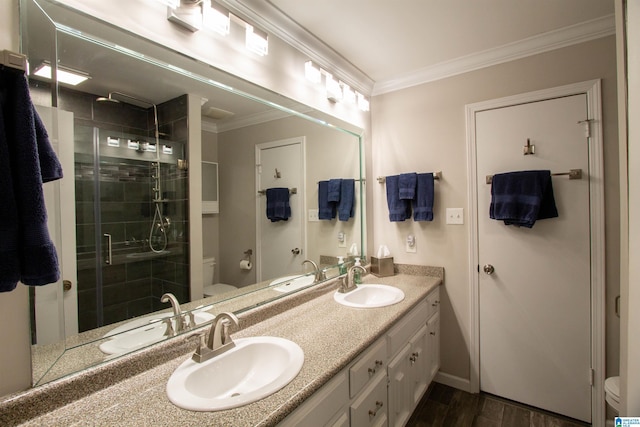 bathroom with a sink, crown molding, a stall shower, and toilet