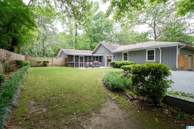 back of property featuring a fenced backyard, a chimney, a sunroom, a patio area, and a lawn