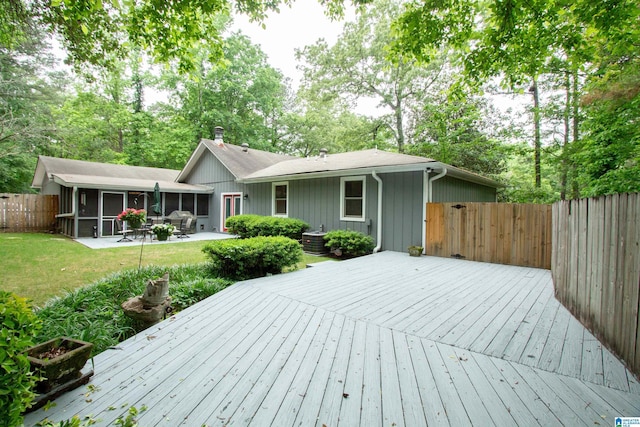 wooden deck with cooling unit, a patio, a fenced backyard, a sunroom, and a lawn