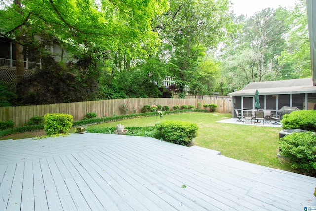 wooden terrace featuring a yard, a fenced backyard, and a sunroom