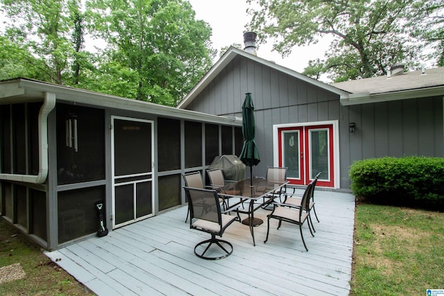 wooden deck with a sunroom and outdoor dining space