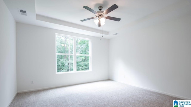 carpeted spare room with visible vents, baseboards, and ceiling fan