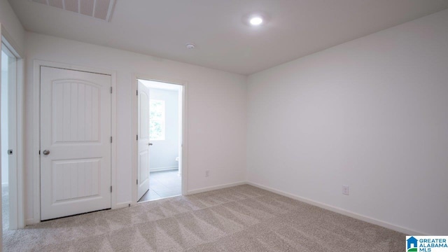 carpeted spare room featuring baseboards and visible vents