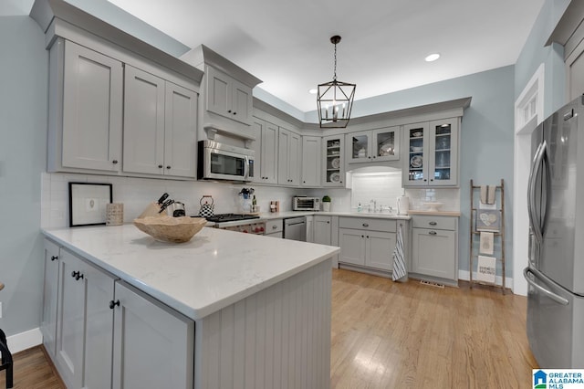 190 Drennen Park Cir, Hayden, AL 35079 - kitchen with appliances with stainless steel finishes, a peninsula, decorative backsplash, a chandelier, and glass insert cabinets