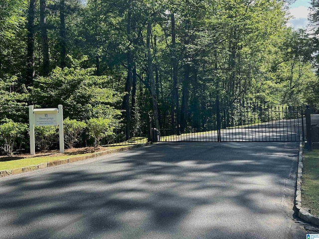 190 Drennen Park Cir, Hayden, AL 35079 - view of asphalt road featuring a gate, curbs, and a wooded view