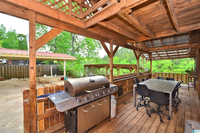 wooden terrace featuring fence and a grill