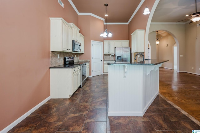 kitchen featuring visible vents, ornamental molding, a peninsula, baseboards, and stainless steel appliances