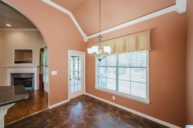 unfurnished dining area with crown molding, arched walkways, baseboards, and a tiled fireplace