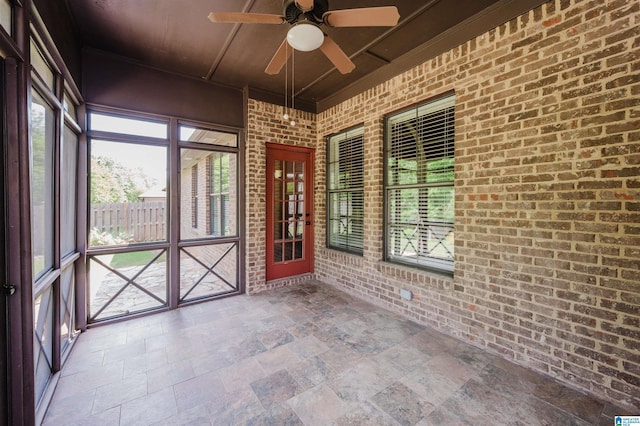 unfurnished sunroom featuring a ceiling fan