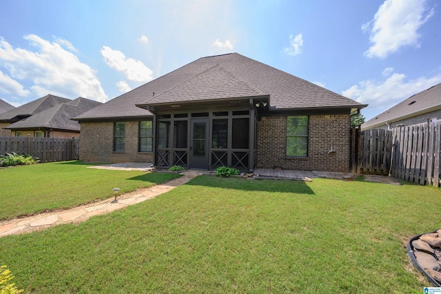 back of property featuring a fenced backyard, brick siding, a sunroom, a shingled roof, and a lawn