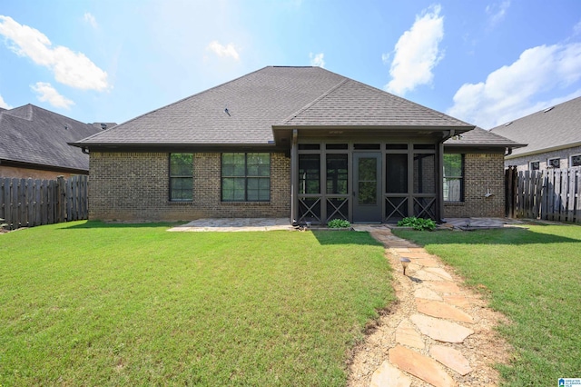 rear view of house with brick siding, a fenced backyard, a yard, and a sunroom