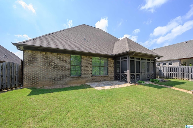 back of property with a yard, brick siding, a fenced backyard, and a sunroom