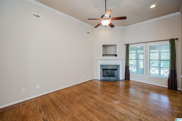 unfurnished living room with a ceiling fan, visible vents, a tiled fireplace, and wood finished floors