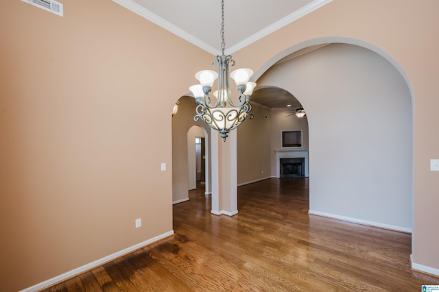 unfurnished dining area with arched walkways, visible vents, ornamental molding, and wood finished floors