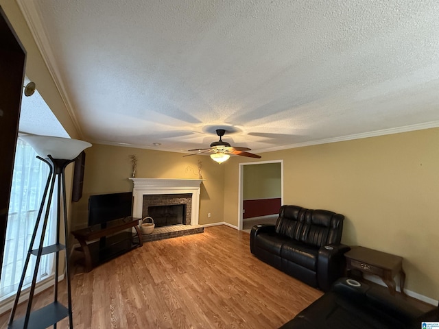living area featuring baseboards, a ceiling fan, a textured ceiling, and a fireplace