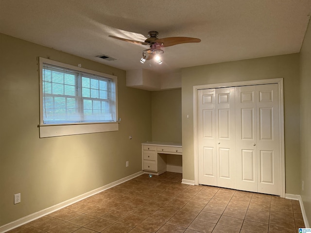 unfurnished bedroom with tile patterned flooring, baseboards, visible vents, and a closet