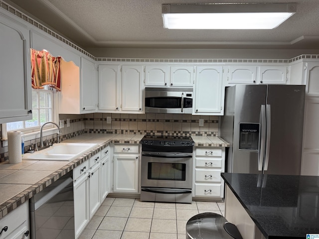 kitchen featuring white cabinets, stainless steel appliances, a sink, and backsplash
