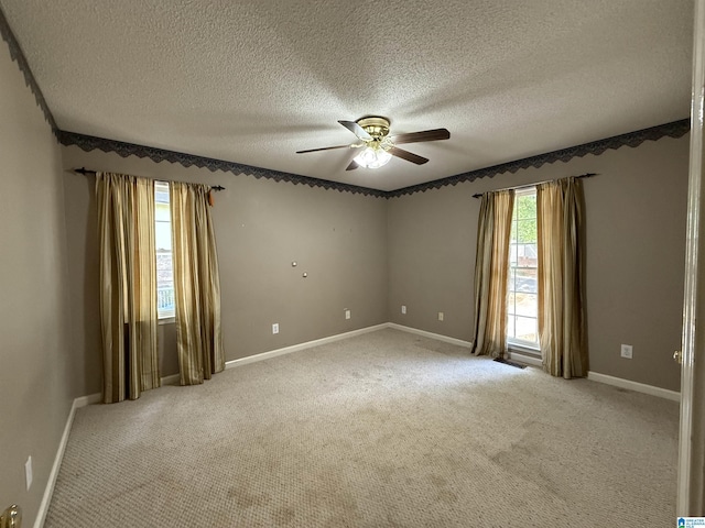 empty room with baseboards, ceiling fan, a textured ceiling, and light colored carpet