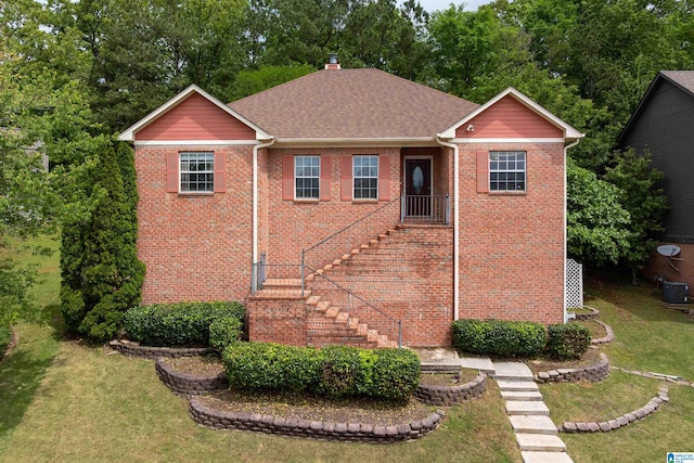 view of front of house with a front yard, roof with shingles, a chimney, and brick siding