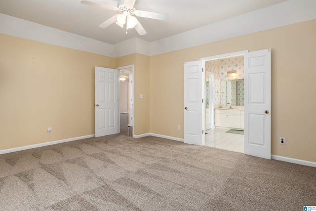 unfurnished bedroom featuring baseboards, ceiling fan, ensuite bath, and carpet flooring