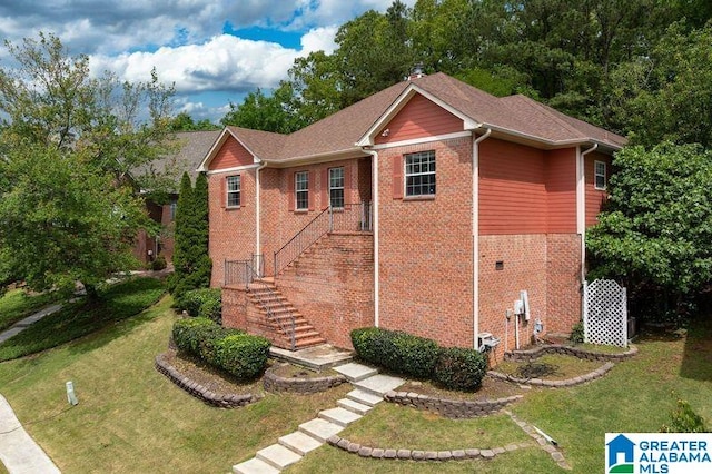 view of front of house featuring stairs, a front yard, and brick siding