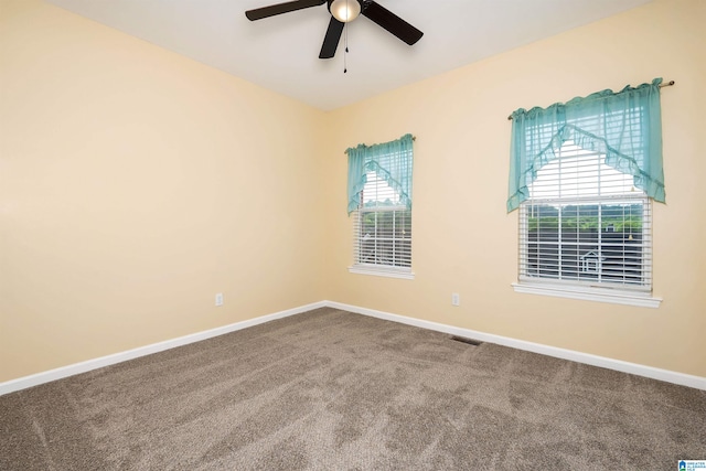 unfurnished room with a healthy amount of sunlight, a ceiling fan, carpet flooring, and baseboards