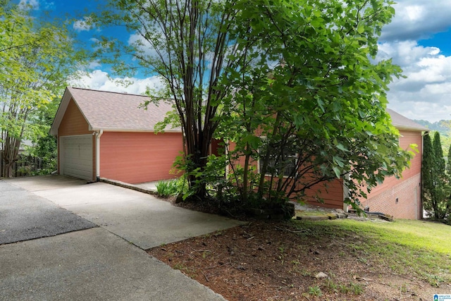 view of home's exterior with an outbuilding, a detached garage, and a shingled roof