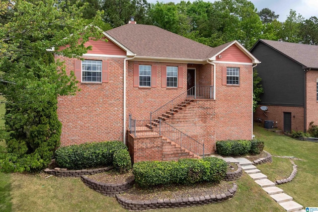 view of front of home with cooling unit, stairs, a shingled roof, a front lawn, and brick siding