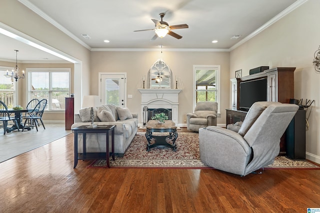 living room with visible vents, baseboards, a fireplace, wood finished floors, and ceiling fan with notable chandelier