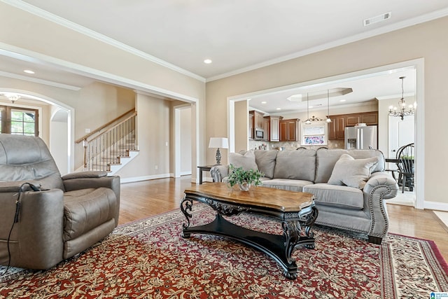 living room featuring stairway, a chandelier, visible vents, baseboards, and light wood-type flooring