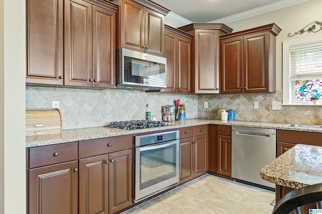 kitchen with tasteful backsplash, light stone countertops, appliances with stainless steel finishes, a sink, and crown molding
