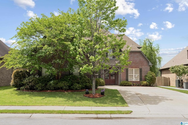 obstructed view of property featuring driveway, a front yard, french doors, and brick siding