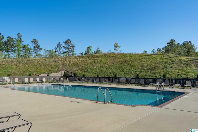 community pool with a patio area and fence