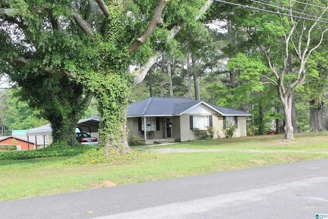 ranch-style home featuring metal roof, a front yard, a detached carport, and stucco siding