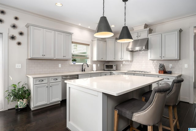 kitchen with a sink, stainless steel appliances, under cabinet range hood, dark wood-type flooring, and a breakfast bar