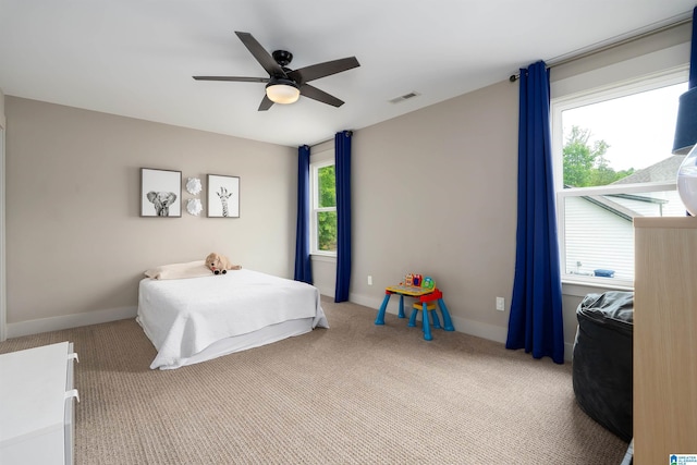 bedroom with light colored carpet, visible vents, a ceiling fan, and baseboards
