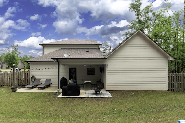 back of house with a patio, a fenced backyard, a shingled roof, and a lawn