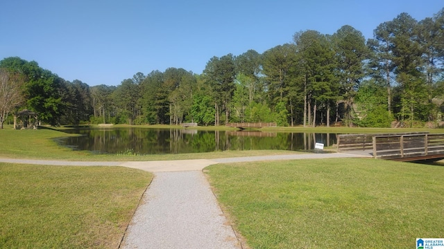 surrounding community featuring a lawn, a water view, and a view of trees