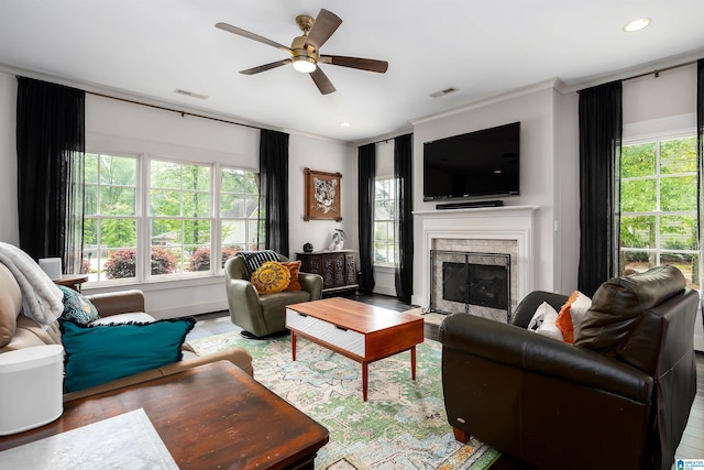 living area with wood finished floors, visible vents, a healthy amount of sunlight, and a ceiling fan