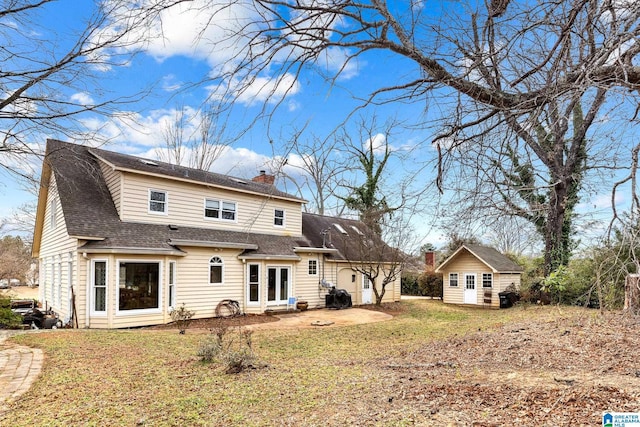 1938 Pleasant Ridge Loop, Sylacauga, AL 35150 - rear view of house featuring a chimney, an outdoor structure, a patio, roof with shingles, and a lawn