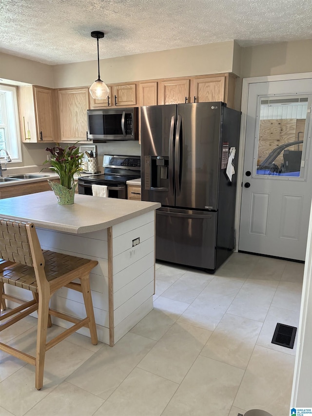 kitchen featuring light brown cabinetry, visible vents, stainless steel appliances, and a sink