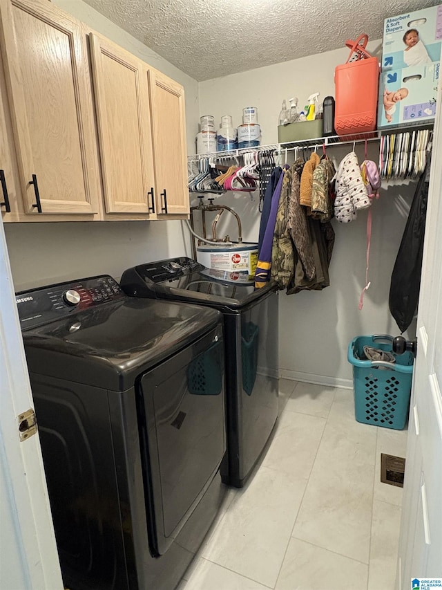 laundry room featuring light tile patterned floors, cabinet space, a textured ceiling, and independent washer and dryer