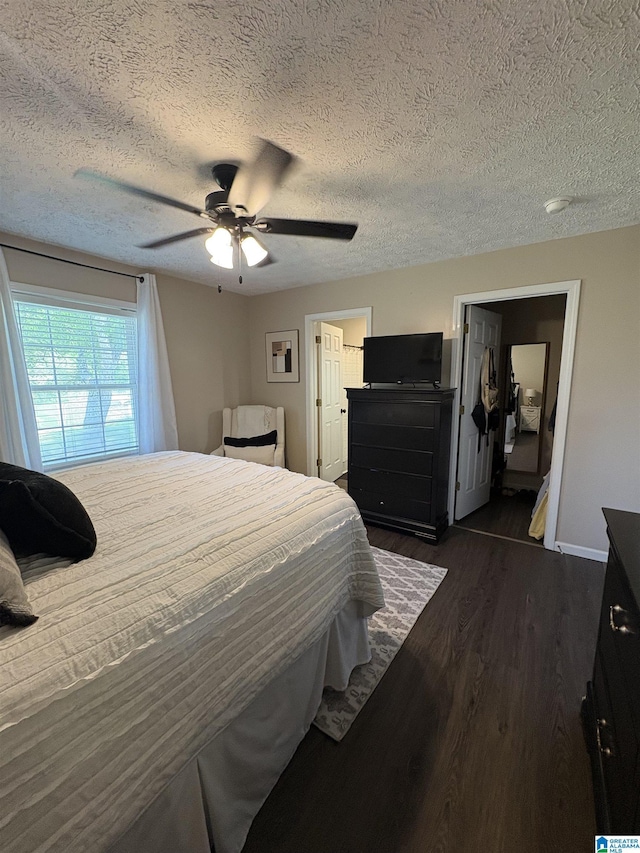 bedroom featuring dark wood-style flooring, ceiling fan, baseboards, and a textured ceiling