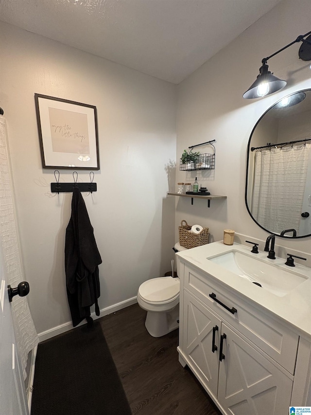 full bathroom featuring toilet, vanity, wood finished floors, and baseboards
